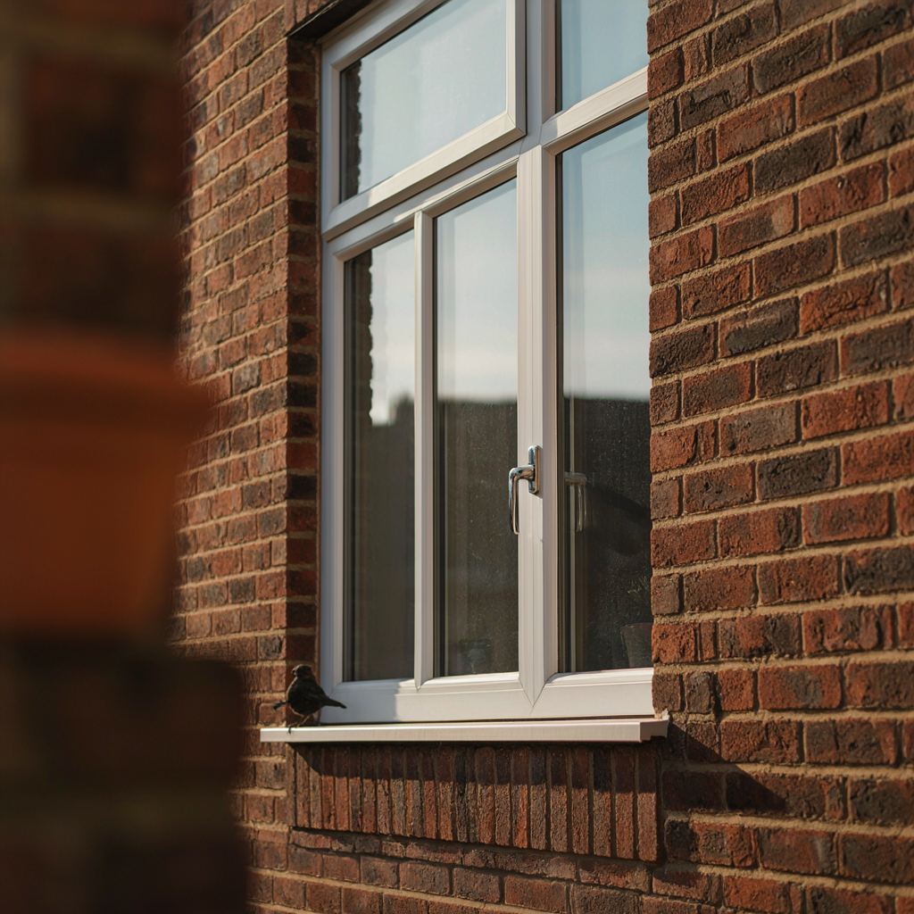 Detailopname van een wit kunststof kozijn met isolatieglas op een bakstenen muur in Utrecht