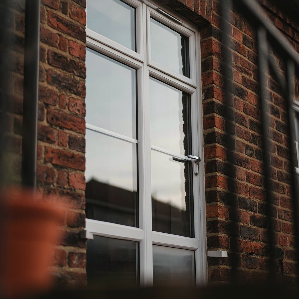 Detailopname van een wit kunststof kozijn met HR++ glas op een bakstenen gevel in Loosdrecht